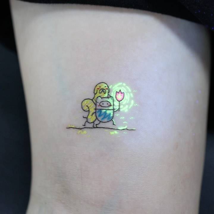 Cartoon style Jake and Finn tattoo placed on the inner arm.
