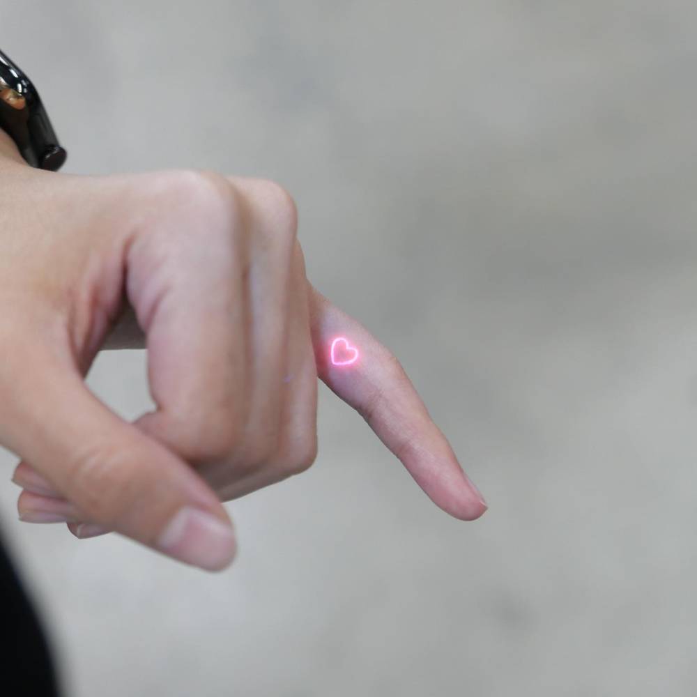 UV ink red heart tattoo in minimalistic style placed on the finger.