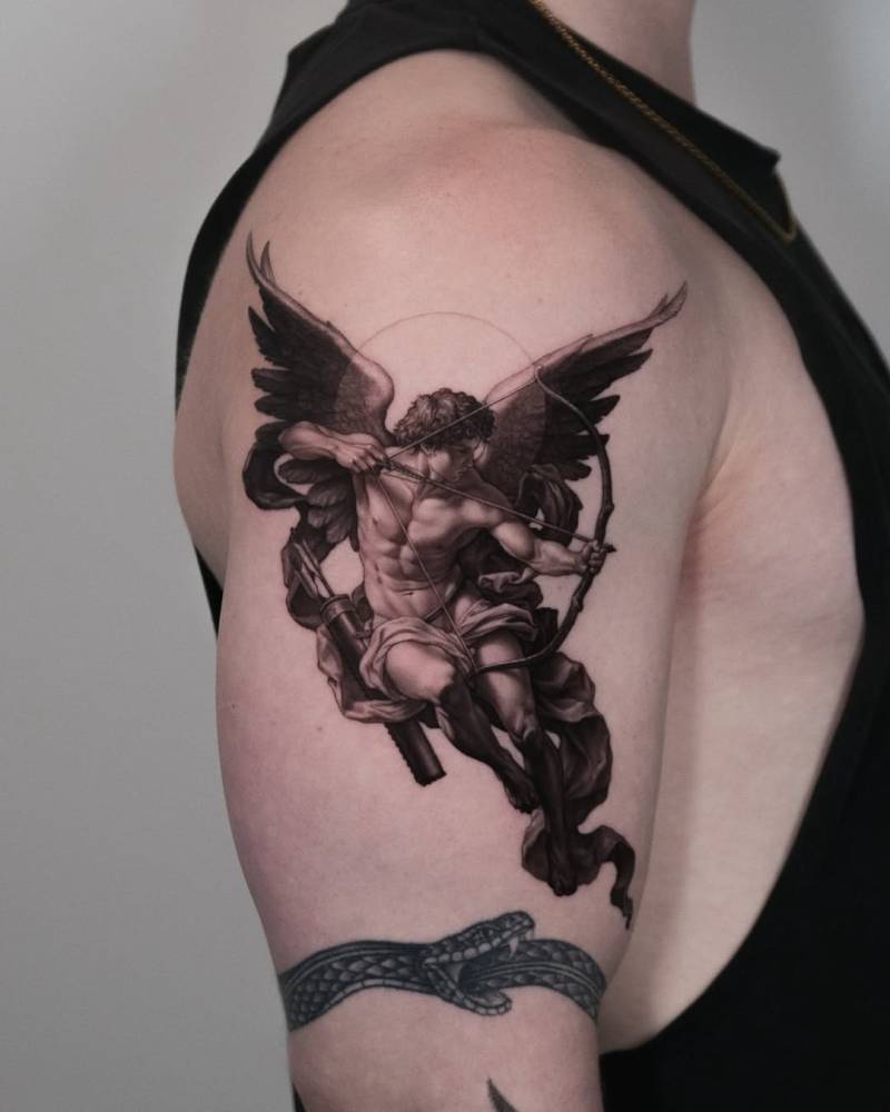 Cupid tattoo in micro-realistic style located on the upper arm.