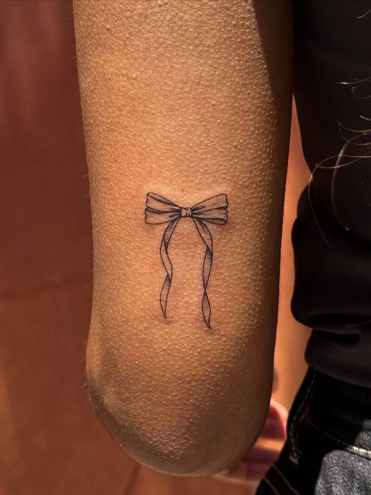 Illustrative style bow tattoo placed on the tricep.