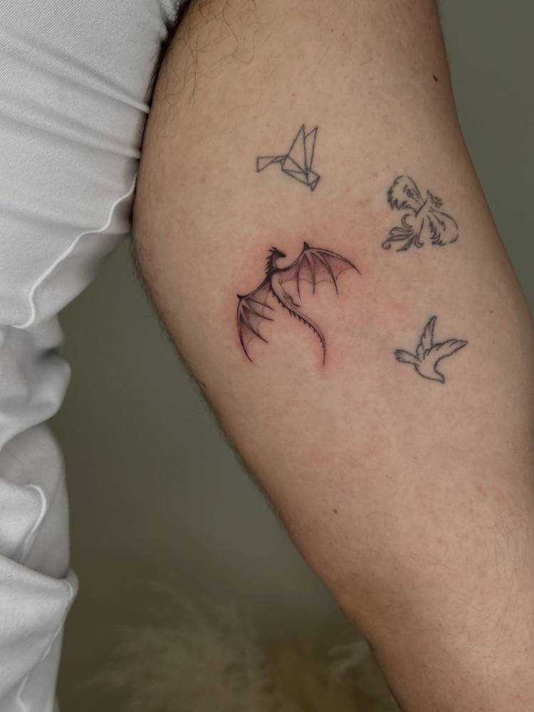 Little dragon tattoo in illustrative style located on the inner arm.