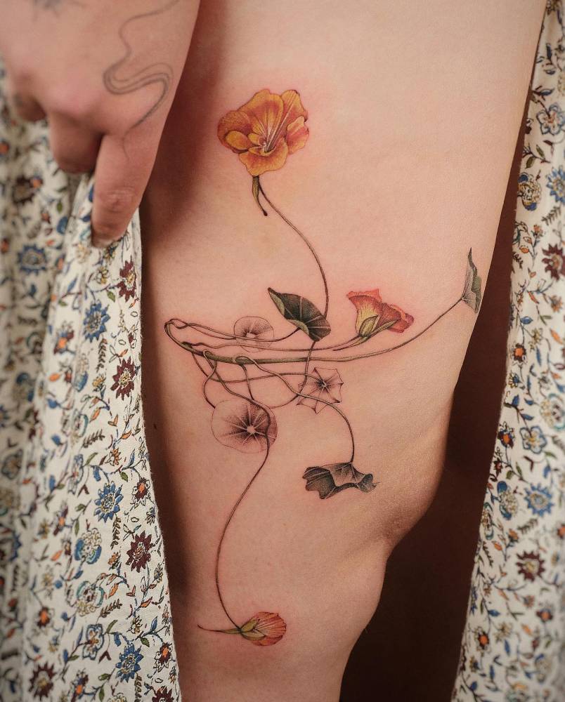 Nasturtium flower tattoo located on the thigh.