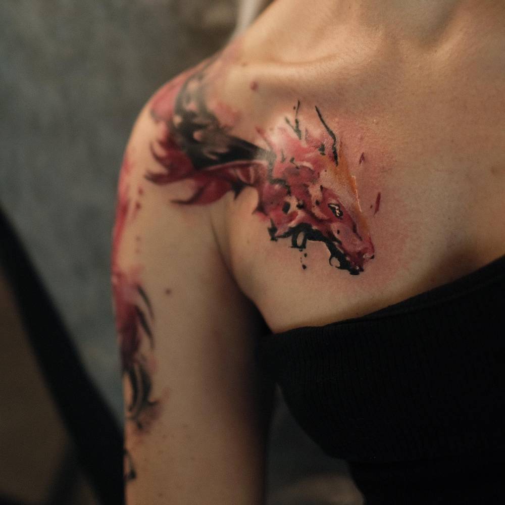 Watercolor style dragon tattoo located on the shoulder.