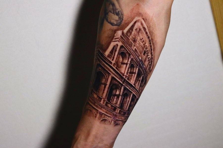 Colosseum tattoo located on the inner forearm, black and grey style.
