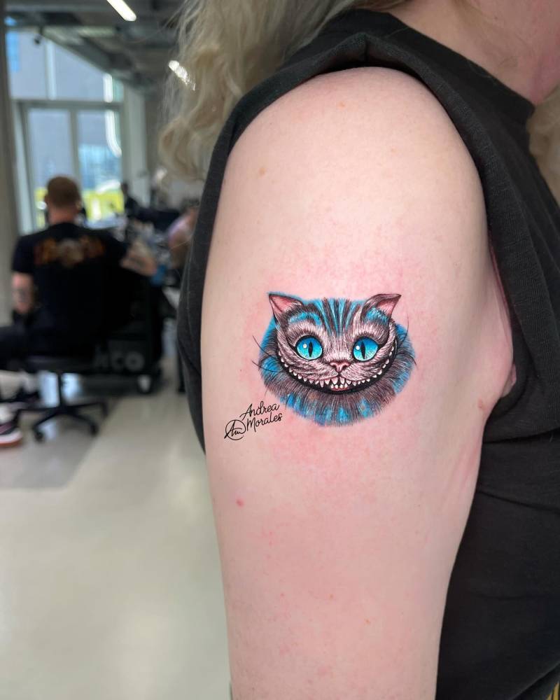 Cheshire Cat portrait tattoo located on the upper arm, cartoon style.