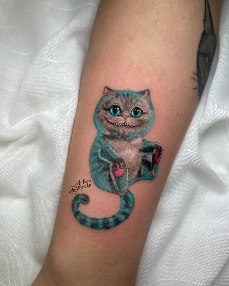 Cartoon style Cheshire Cat tattoo done on the inner forearm.