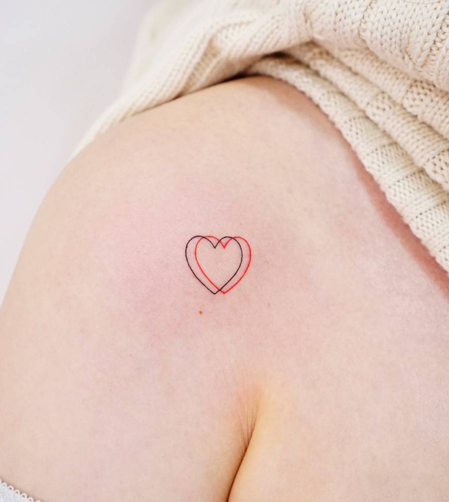 Minimalistic double heart tattoo located on the shoulder.