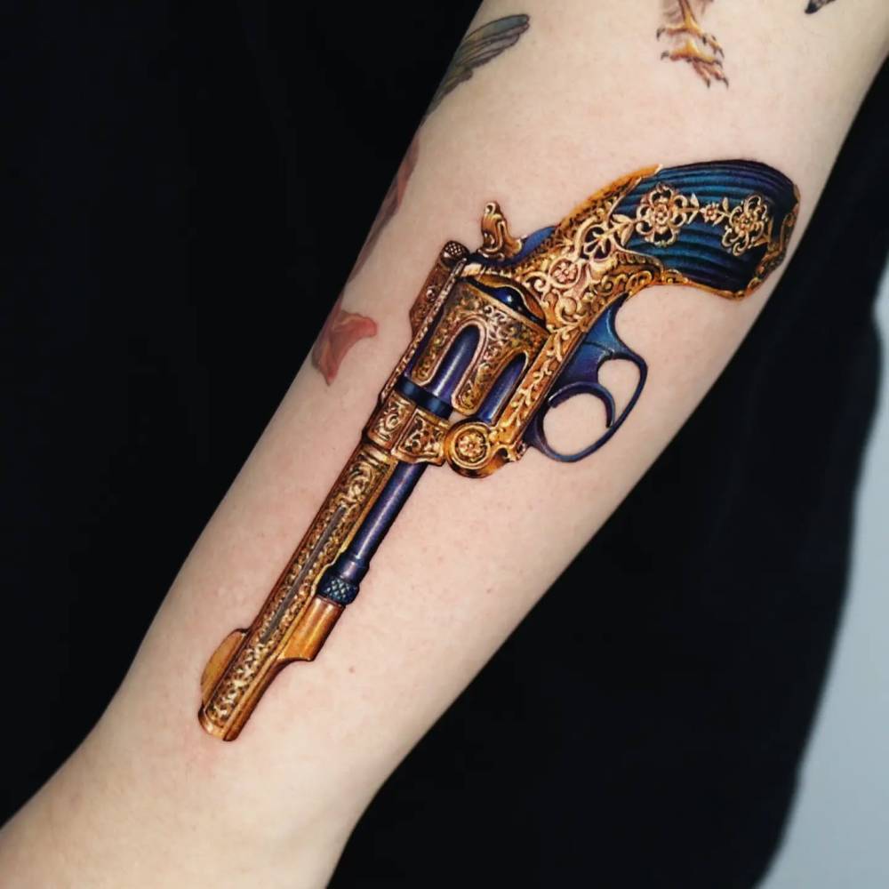Revolver tattoo located on the forearm, realistic style.