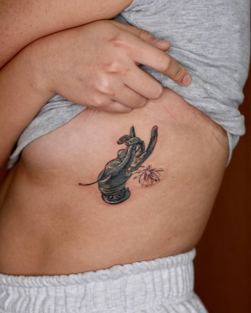 Vitarka Mudra tattoo located on the rib, done in watercolor style.