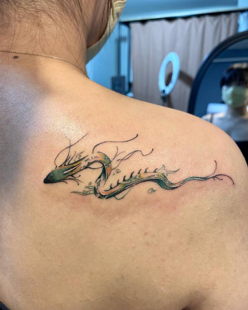 Watercolor style dragon tattoo located on the shoulder blade.