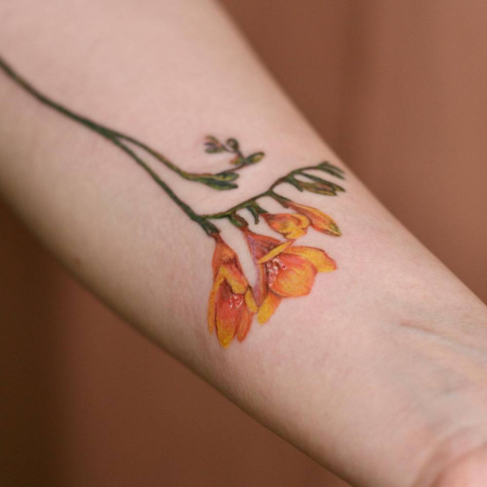 Watercolor style freesias tattoo located on the inner forearm.