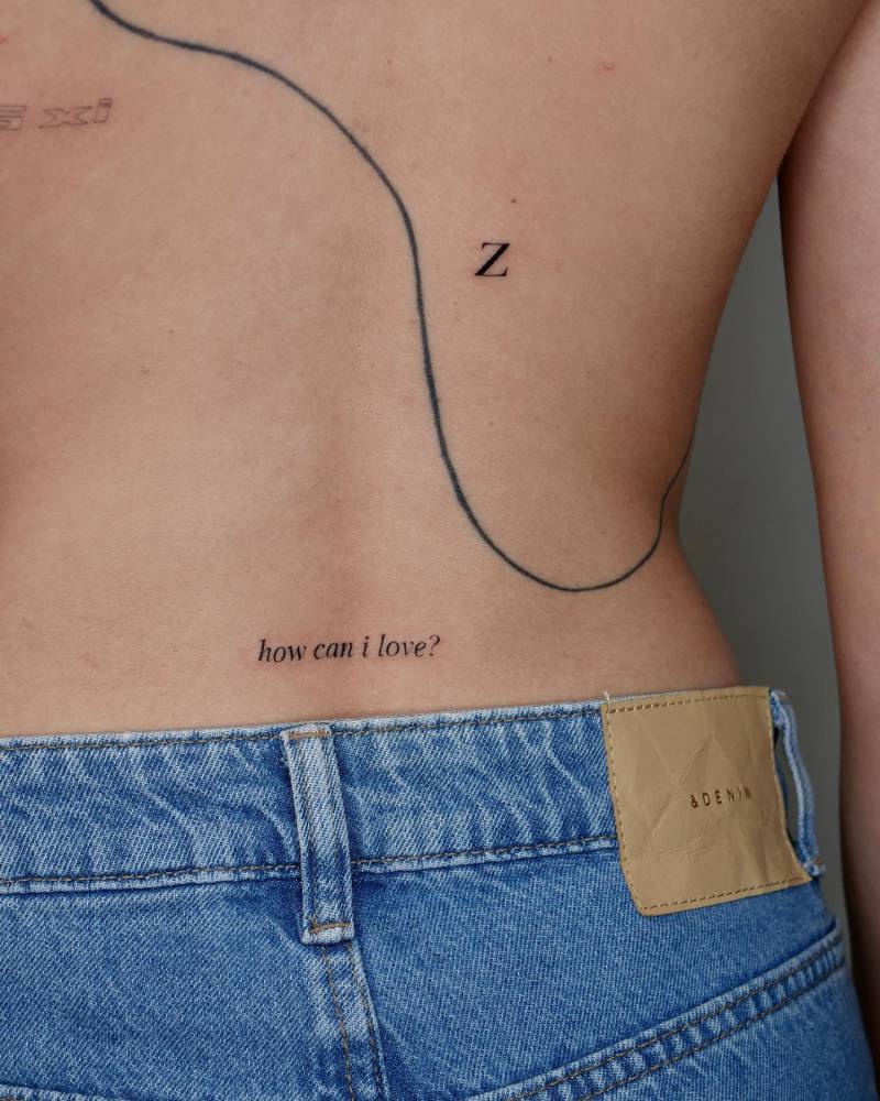 Letter "Z" and "how can I love?" lettering tattoo located on the lower back.