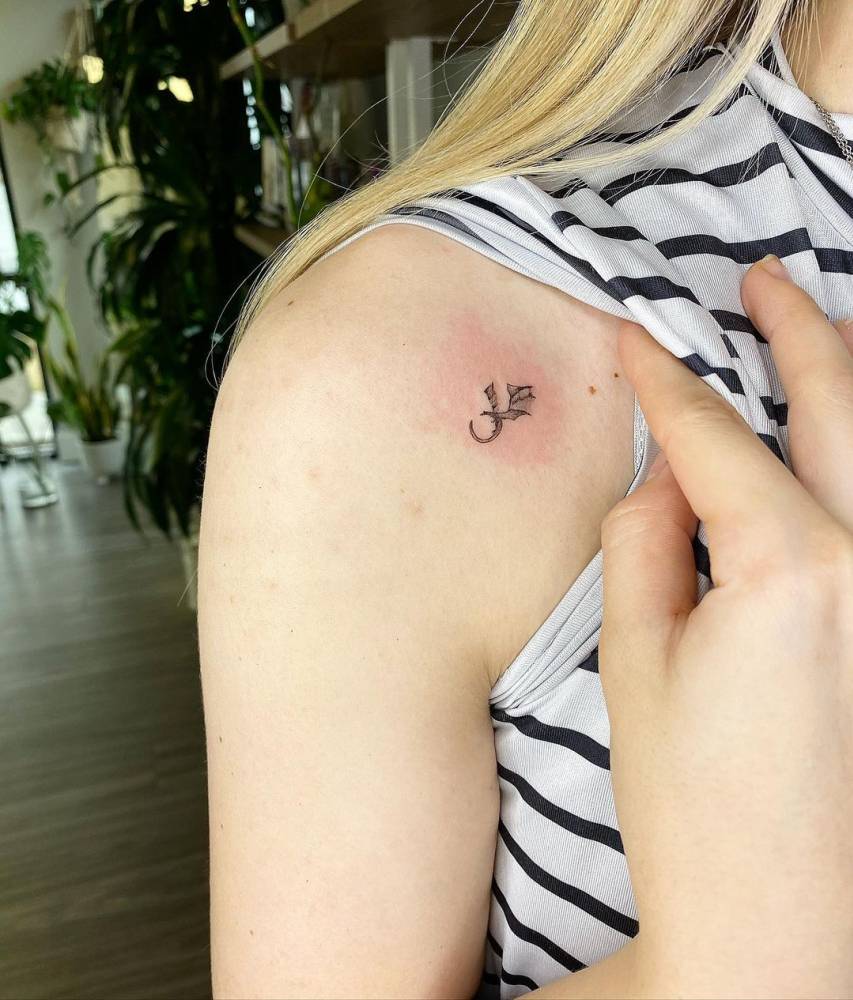 Tiny micro-realistic dragon tattoo located on the shoulder.