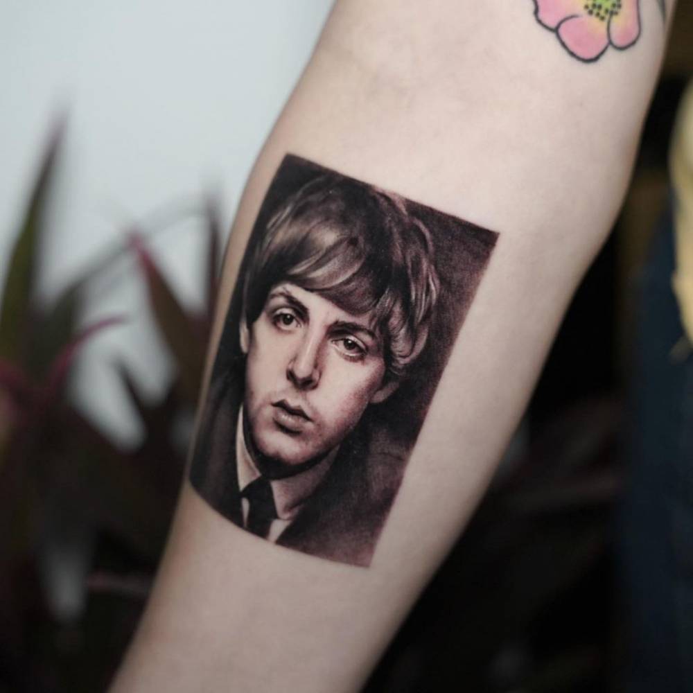 Micro-realistic Paul McCartney portrait tattoo on the inner forearm.