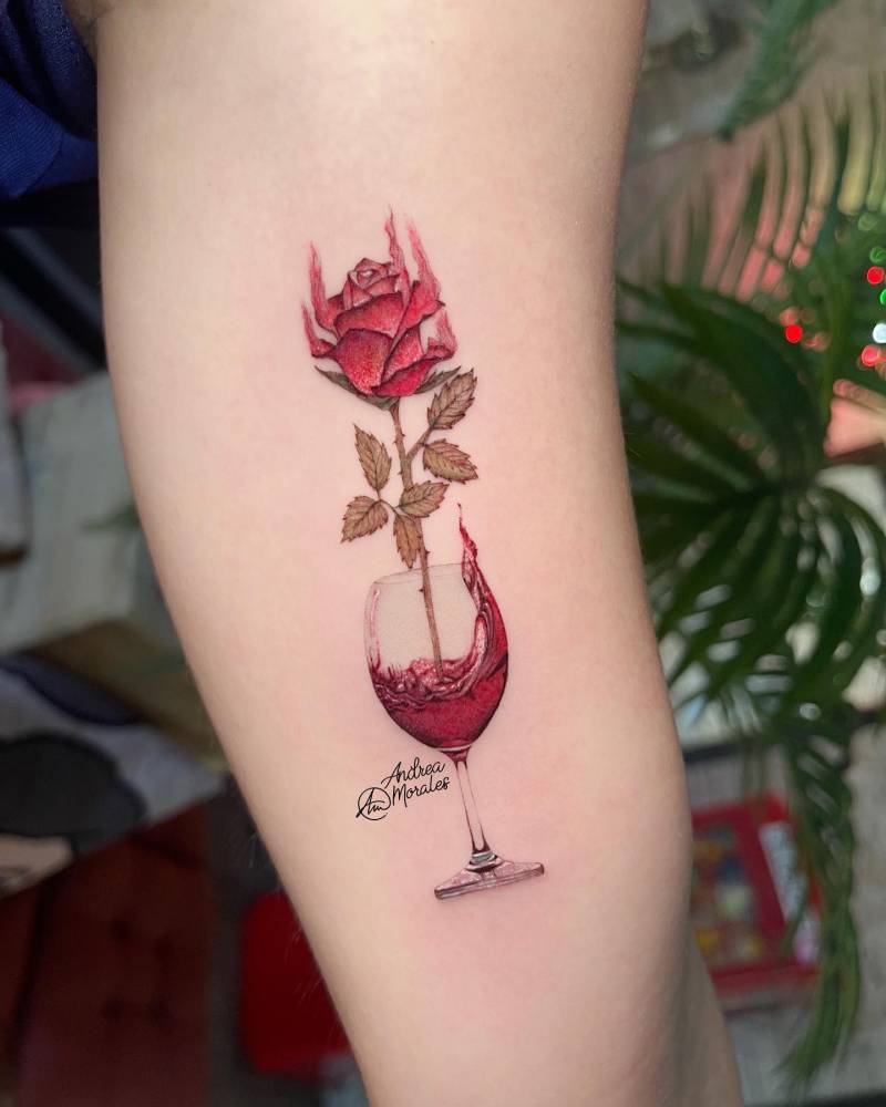 Wine glass and red rose tattoo located on the inner arm.