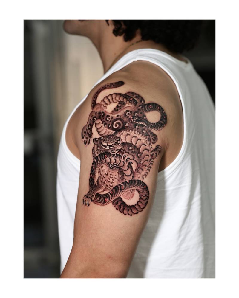 Tiger and snake battle royale tattooed on the upper arm and shoulder.