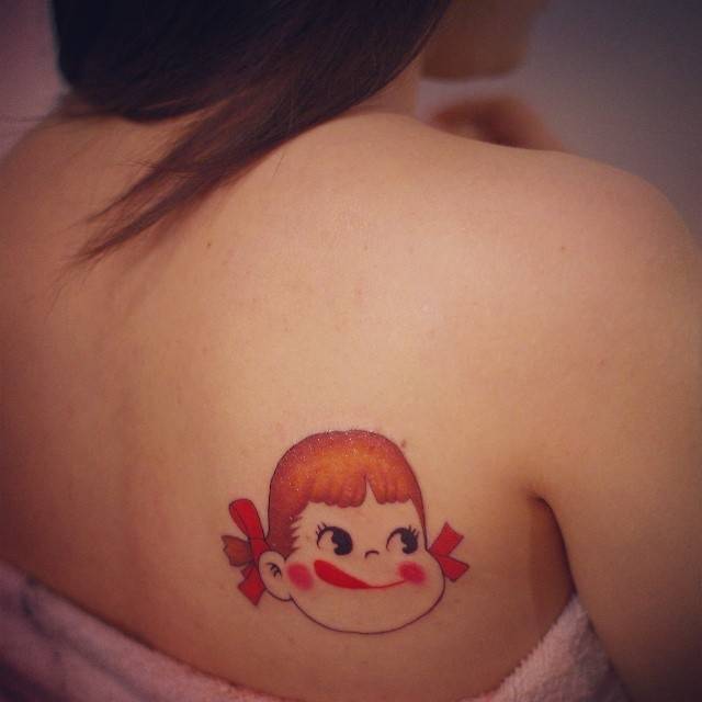 Peko Chan portrait tattoo located on the shoulder blade, cartoon style.
