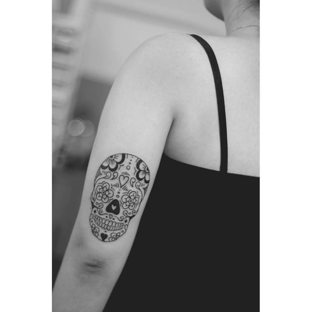 Sugar skull tattoo in illustrative style done on the tricep.
