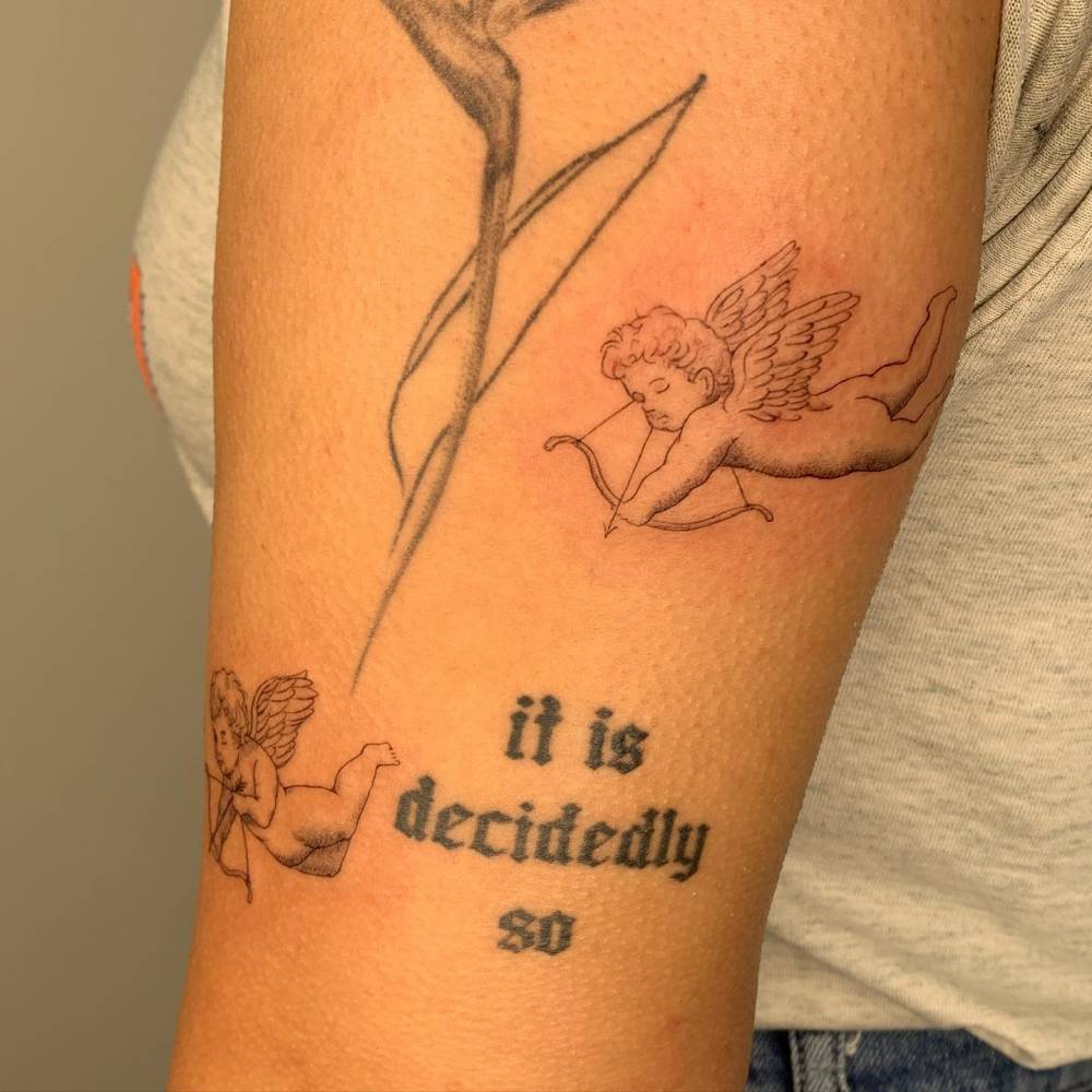 Fine line cupid tattoo done on the upper arm.