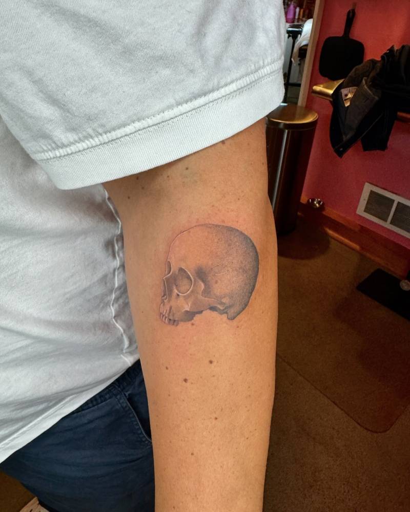 Illustrative style skull tattoo located on the forearm.