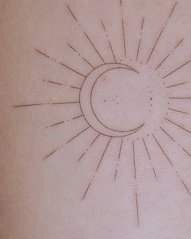 Sun and moon tattoo in fine line style located on the inner forearm.