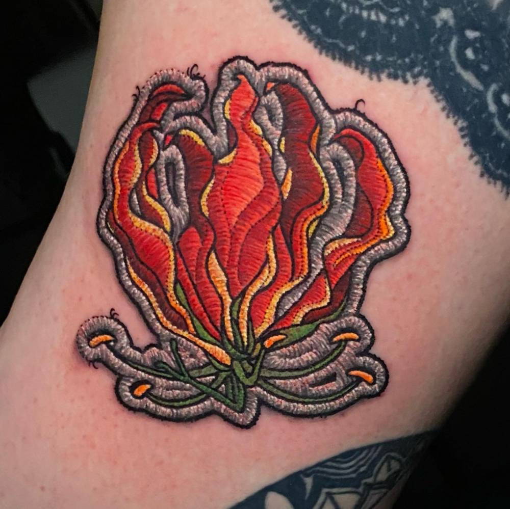 Flame Lily patch tattoo located on the thigh.