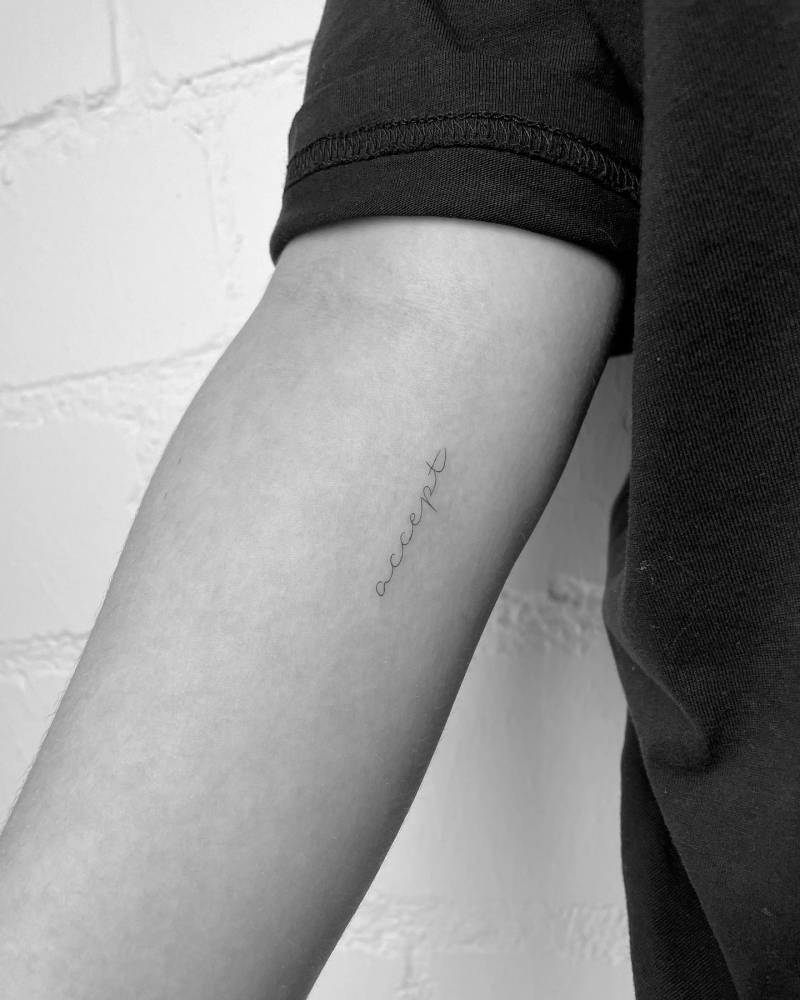 Word "accept" tattooed on the inner forearm.