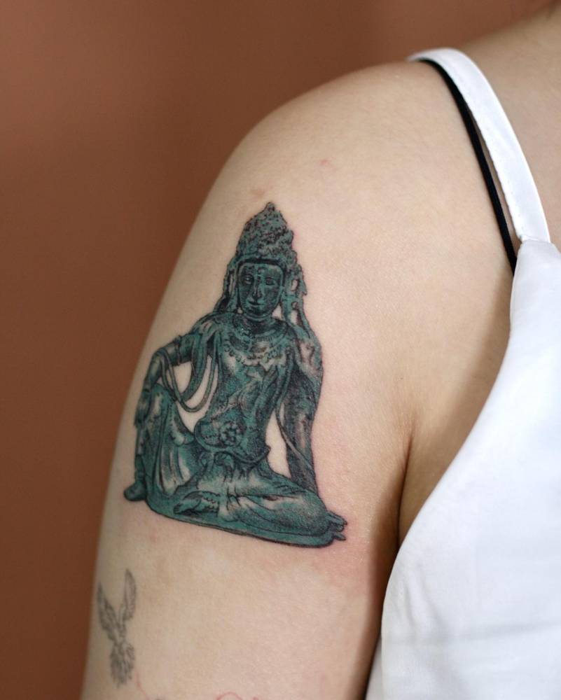 Buddha tattoo located on the shoulder, illustrative style.