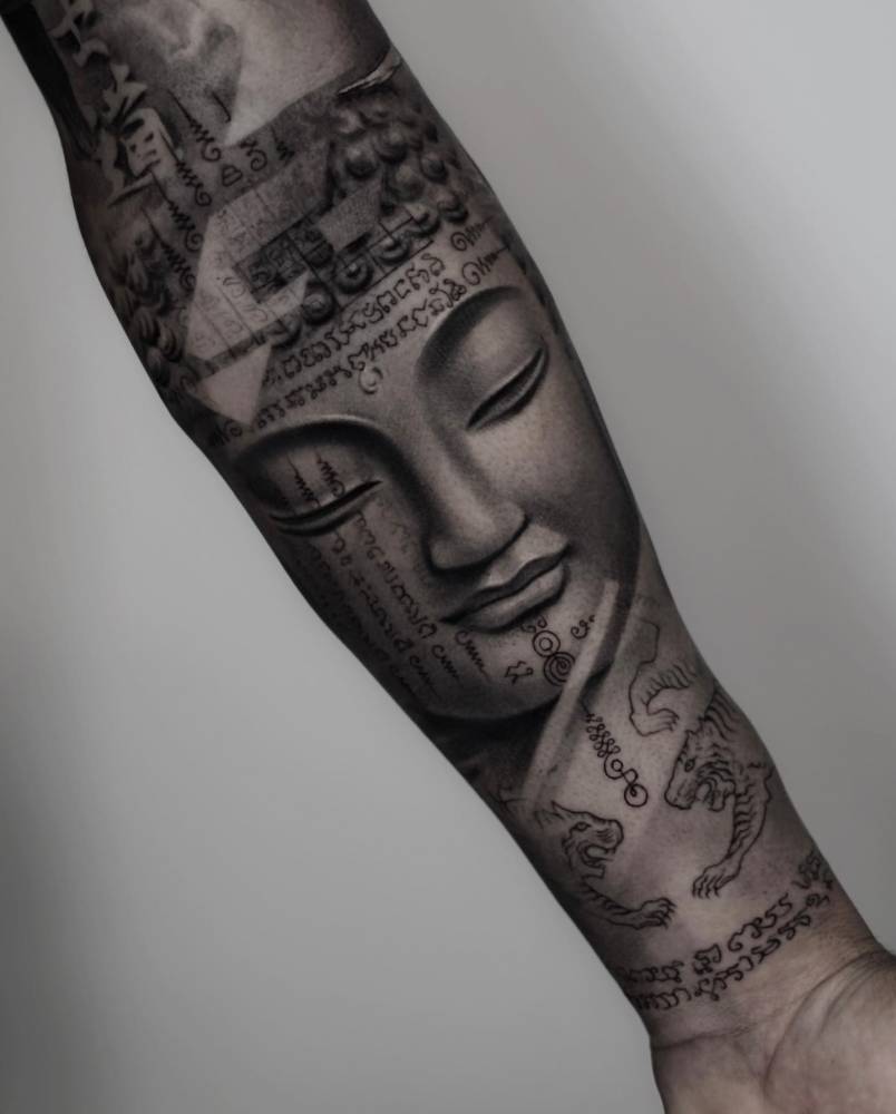Buddha tattoo in black and grey style located on the inner forearm.