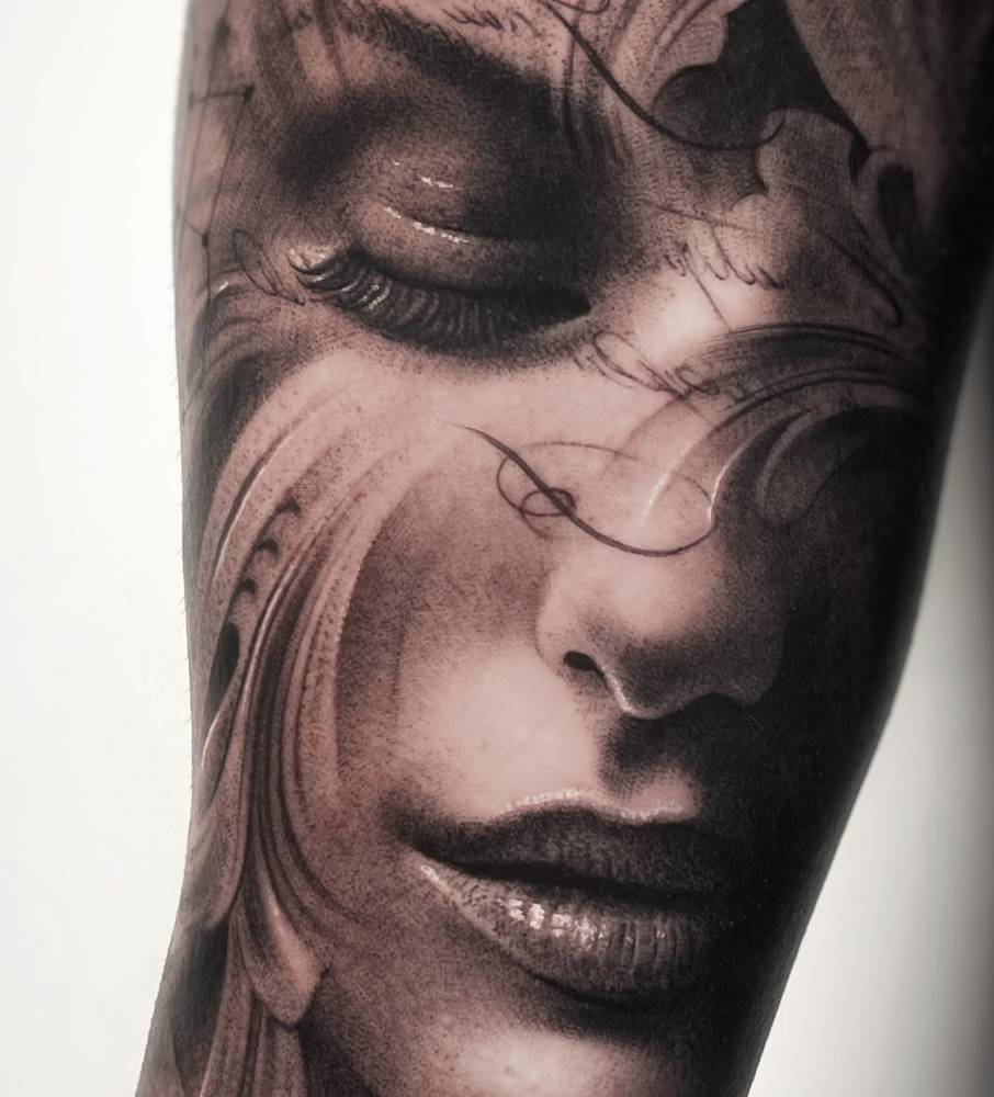Black and grey woman portrait tattoo located on the inner forearm.