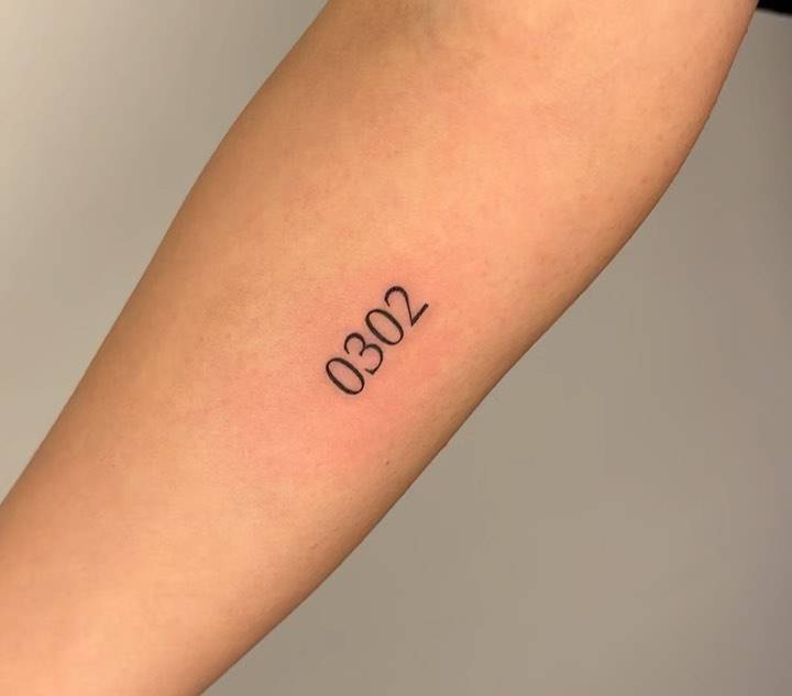 Number "0302" tattooed on the inner forearm.