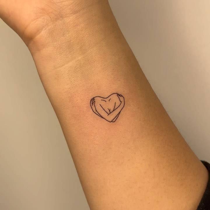 Self hug tattoo located on the wrist, minimalistic style.