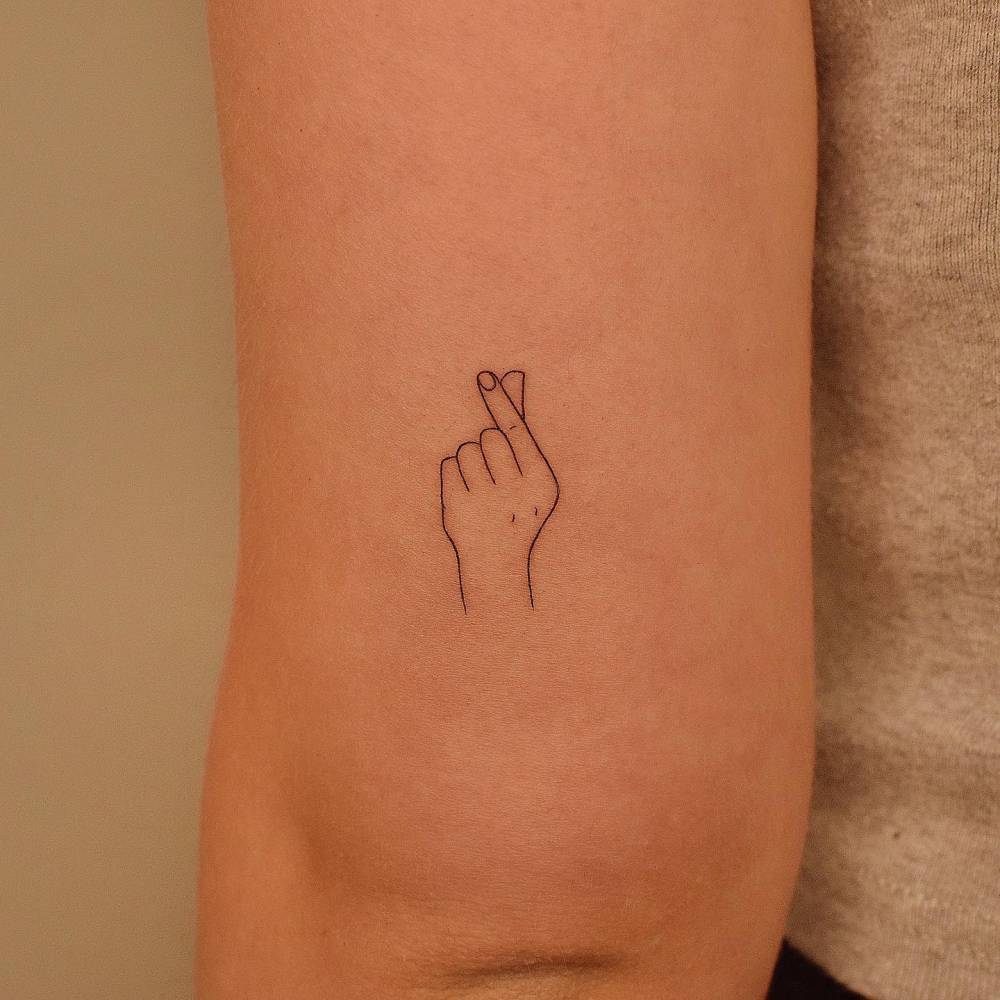 Minimalistic korean finger heart tattoo done on the tricep.