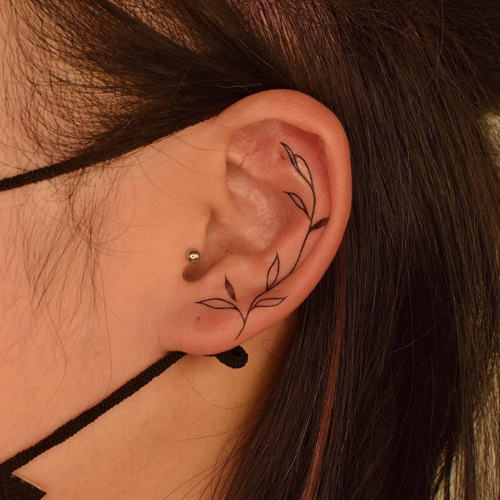 Leaves tattoo located on the ear, minimalistic style.