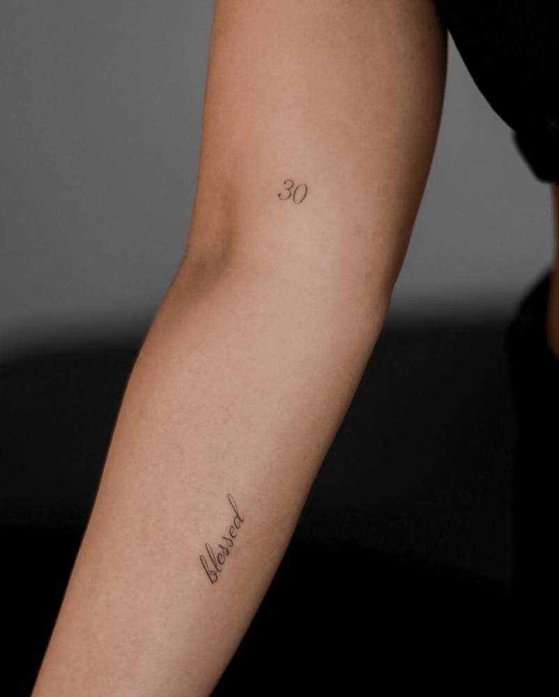 Word "blessed" tattooed on the inner forearm.