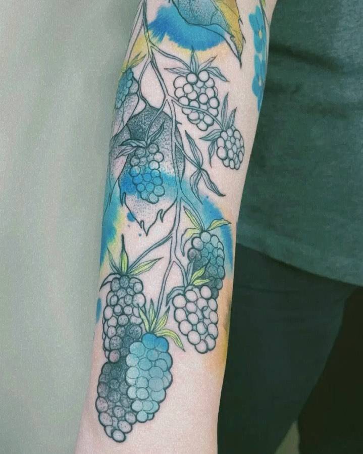Watercolor style blackberries tattooed on the forearm.