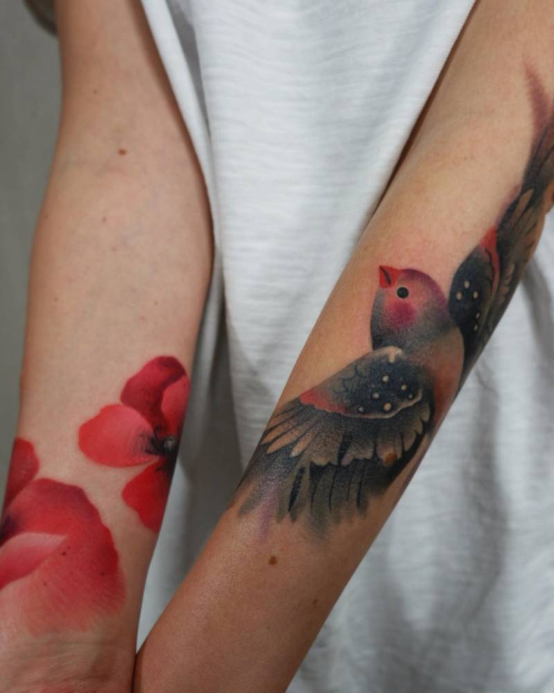 Watercolor style finch and poppy flowers tattooed on the forearms.