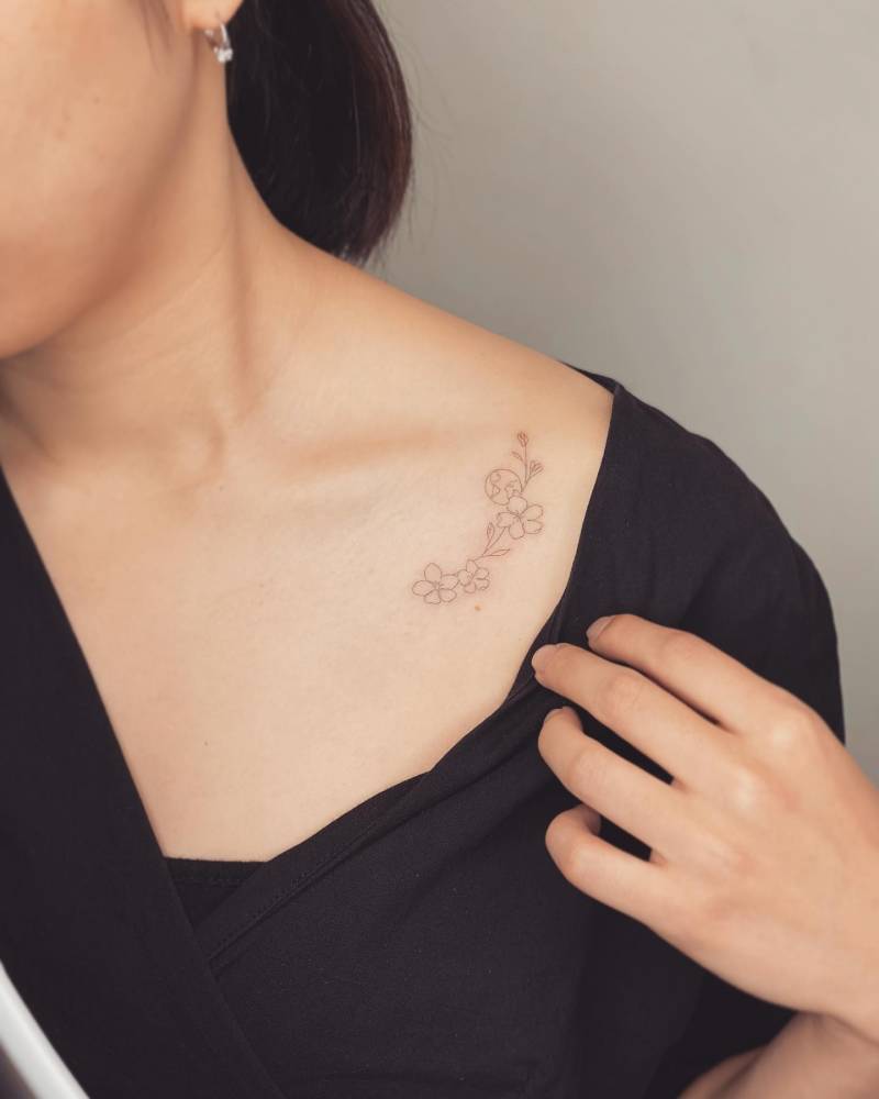 One line cherry blossom and Earth tattoo located on the collarbone.