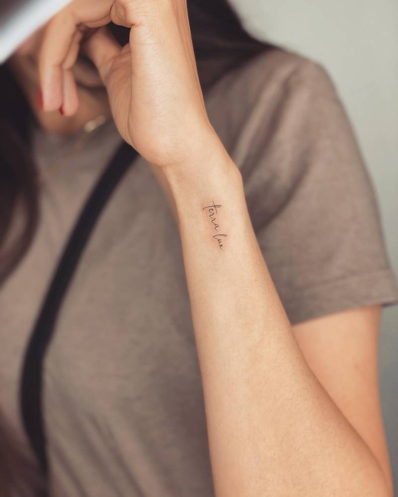 "Terra lux" lettering tattoo handwritten on the wrist.