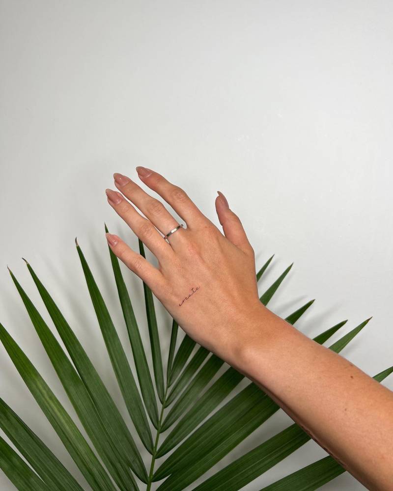 Lettering tattoo of the word "create" located on the hand.