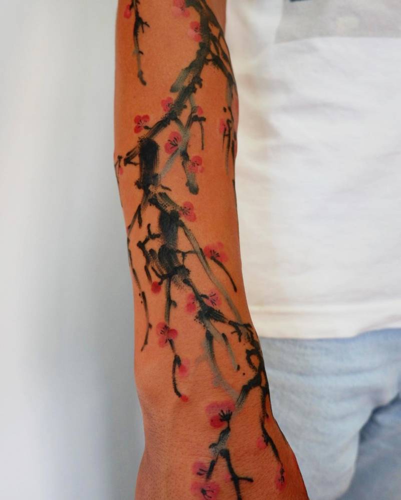 Watercolor style cherry blossom tattoo located on the forearm.