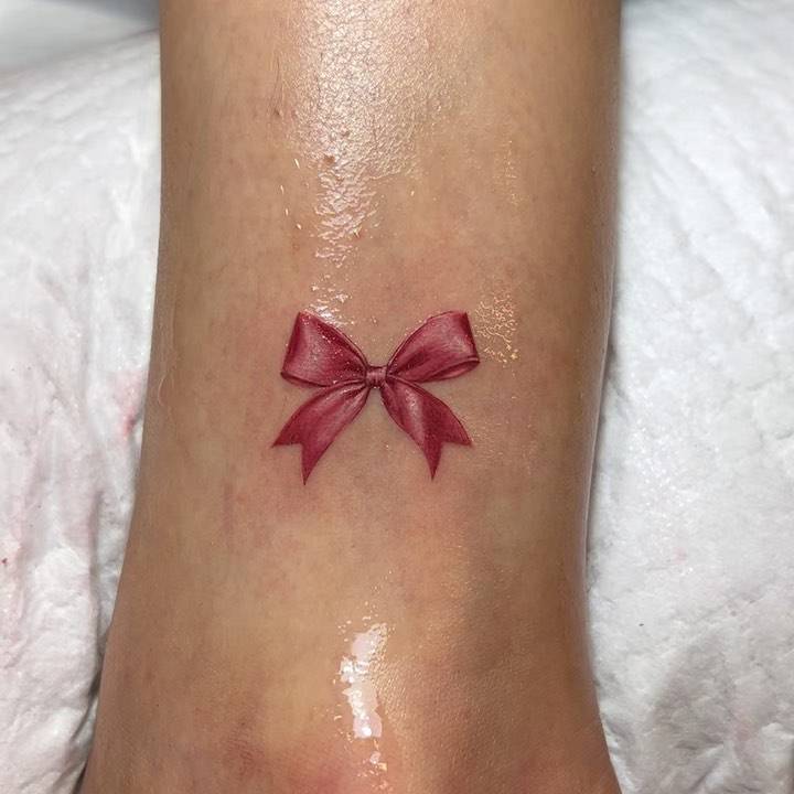 Micro-realistic ribbon tattoo located on the ankle.