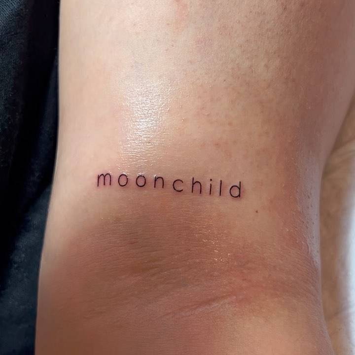Tattoo of the word "moonchild" located on the bicep.