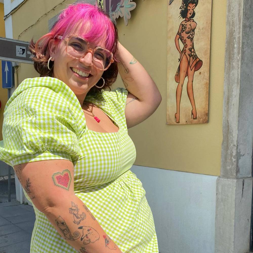 Cross stitch watermelon heart tattoo located on the upper arm.