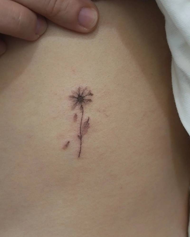 Hand poked daisy flower tattoo done on the rib.