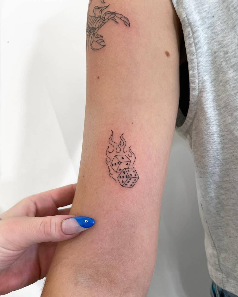 Dice and fire tattoo located on the bicep.