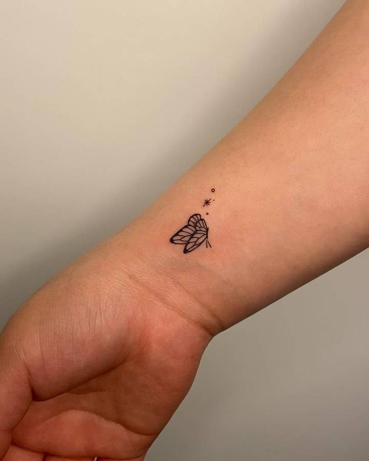 Fine line butterfly tattoo placed on the wrist.