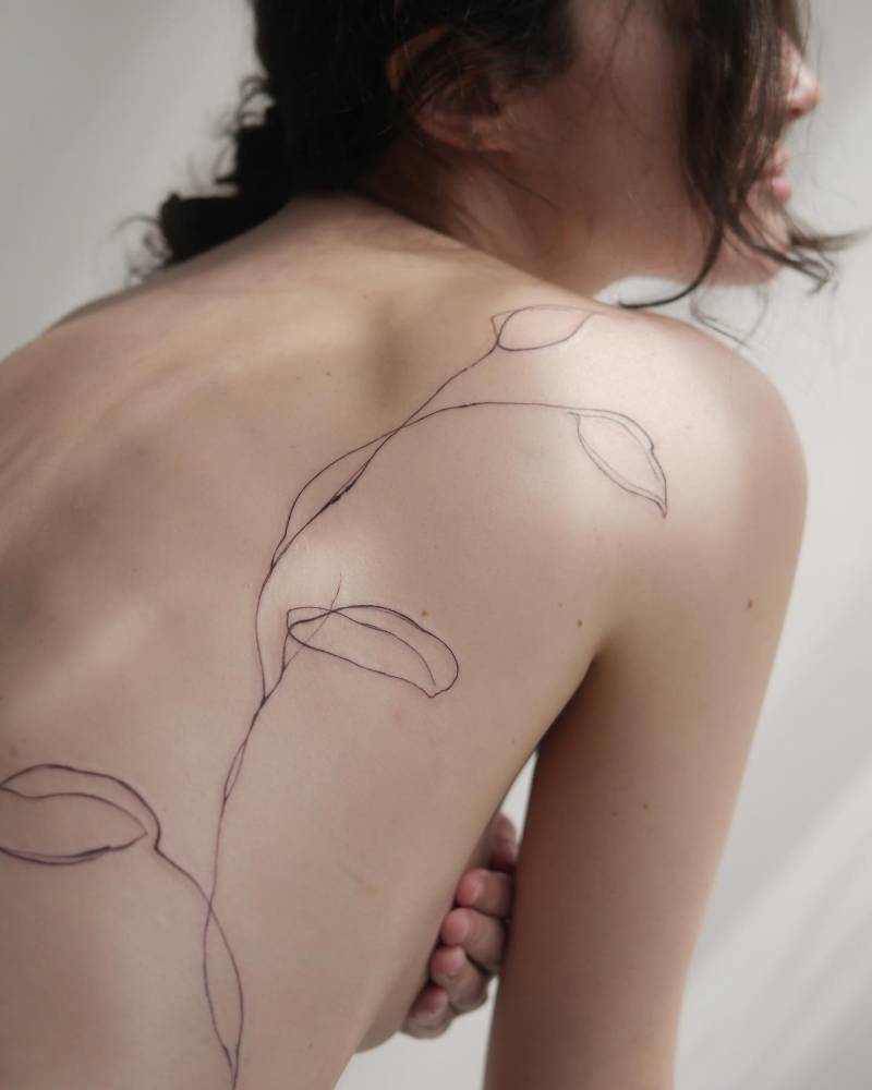 Leaves tattoo located on the back, sketch work style.