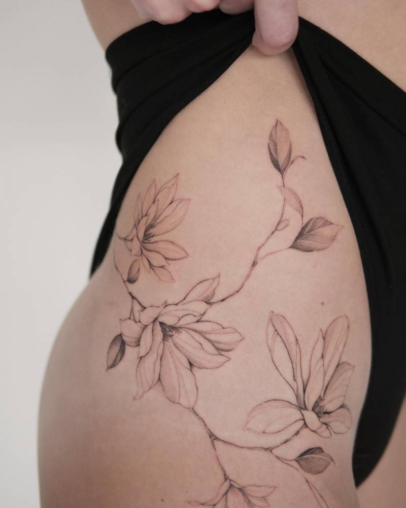 Magnolia flowers tattooed on the hip, illustrative style.