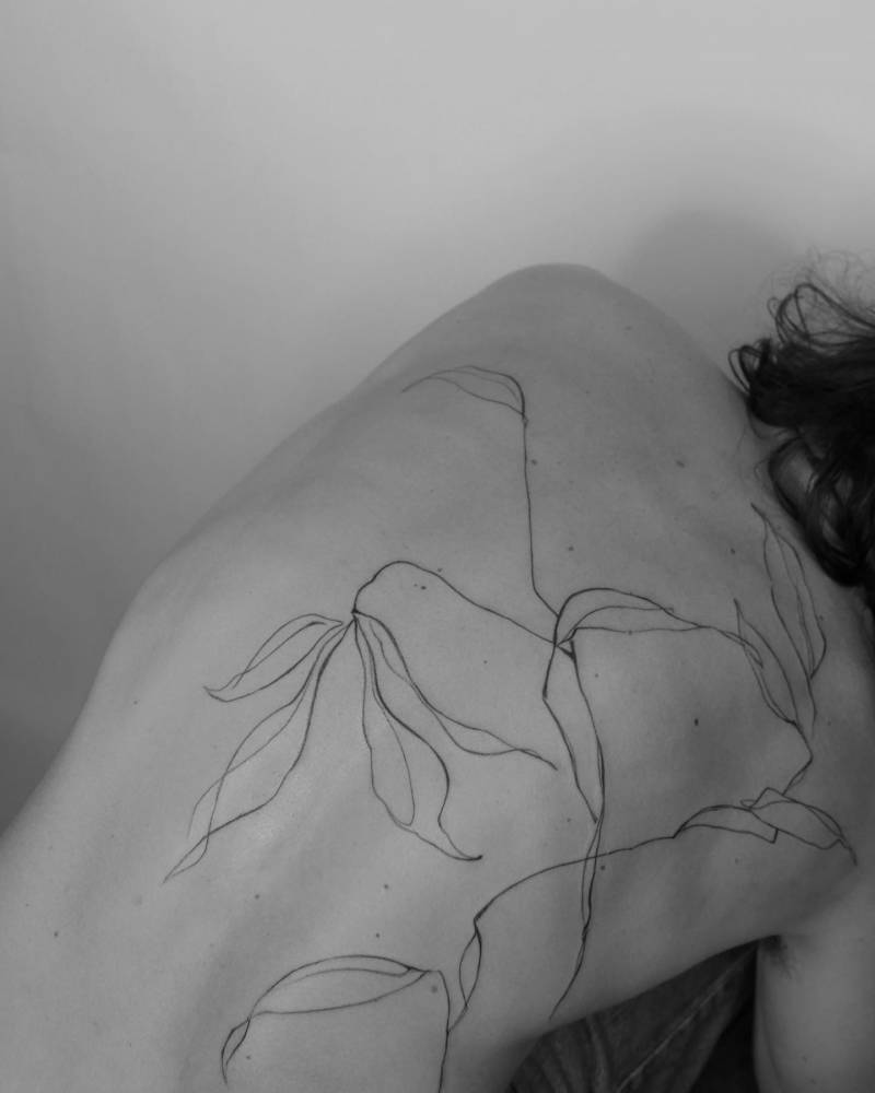 Sketchy style leaves tattoo located on the back.